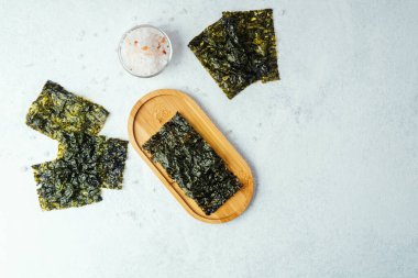 Beyaz arka planda bir kase tuzlu kavrulmuş yosun atıştırmalığı