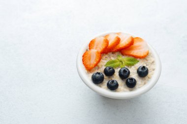 Beyaz arka planda yulaf ezmesi, çilek ve yaban mersini manzarası