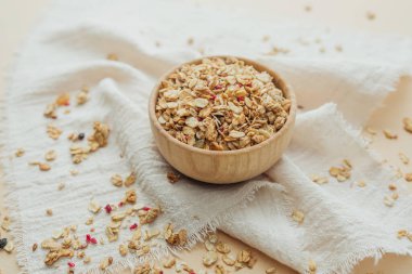 Tahta kasede yumuşak beyaz kumaş arka planda granola.