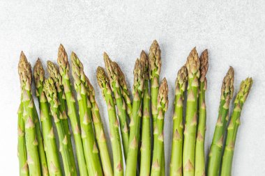 Kıtır yeşil kuşkonmaz mızrakları pürüzsüz gri bir yüzeye serilmişti..