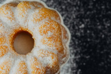 Siyah arkaplanda pudra şekerli kek 