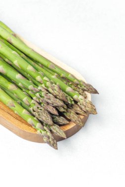 Taze toplanmış yeşil kuşkonmaz ahşap servis tahtasına güzelce yerleştirilmiş..