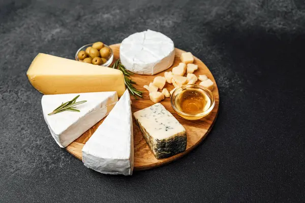 Tahta bir tahtanın üzerinde nefis bir peynir, zeytin ve bal seçimi..