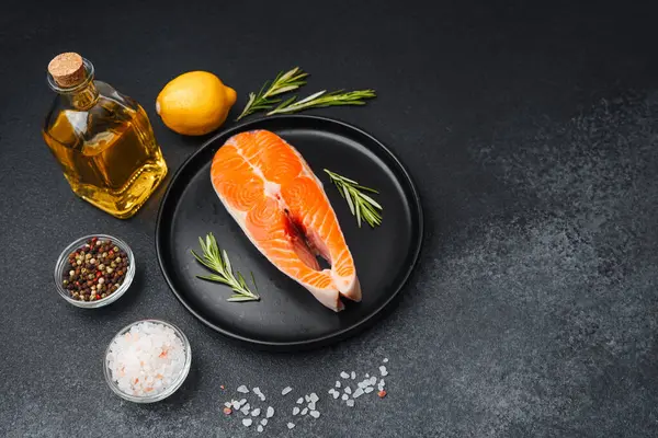 Bir tabakta somon fileto ve yanında otlar, limon ve yemek hazırlama çeşnisi..