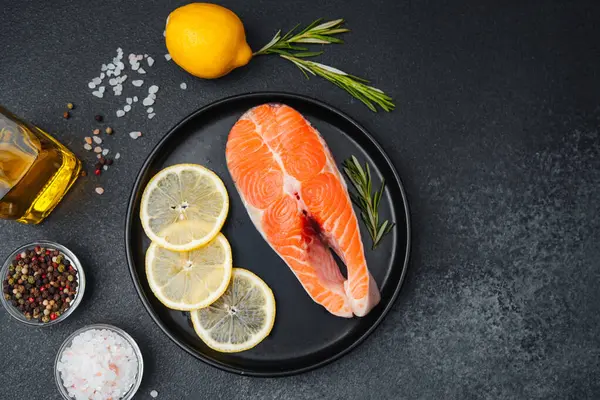 Limon dilimli çiğ somon filetosu ve pişirme hazırlıkları için taze otlar..