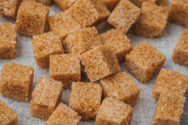 Kahverengi şeker küpleri yoğun bir şekilde açık kumaş yüzeyine paketlenmiştir..