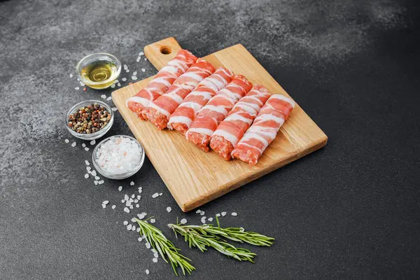 Pastırmaya sarılı çiğ et ruloları ahşap tahtaya baharatlı.