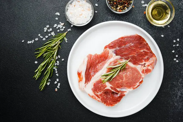 Biberiye ve baharatlı, beyaz tabakta pişmemiş biftek.