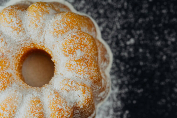 Bundt cake with powdered sugar on black background 