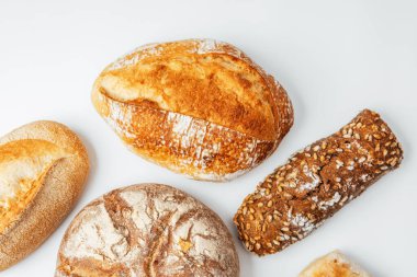 Farklı türde taze pişmiş ekmek hafif bir arka planda güzel bir şekilde düzenlenir..