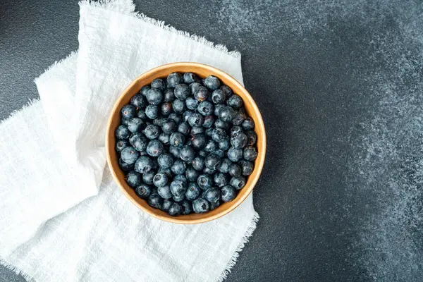 Bir kase taze yaban mersini kumaşın üzerine oturup renklerini renklendirir..
