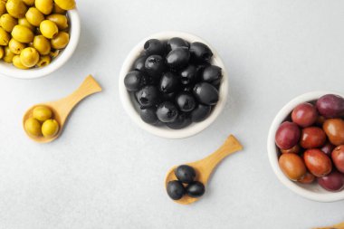 Kase içinde yeşil, siyah ve kalamata zeytinler ve ahşap kaşıklar.