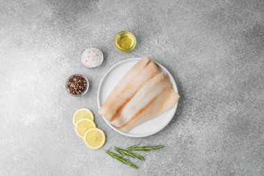 Gri arka planda baharat içeren ham pollock fileto.