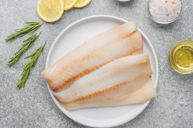 Gri arka planda baharat içeren ham pollock fileto.