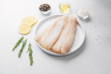 Beyaz arka planda limonlu ve biberiyeli ham pollock fileto.