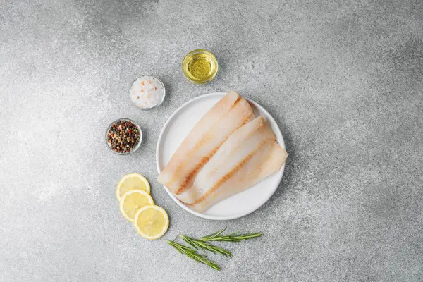 Gri arka planda baharat içeren ham pollock fileto.