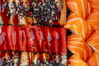 Susamlı ve soslu somon balığı ve yılan balıklı suşi rulolarını kapatın.