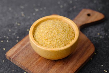 Çatlak buğday, siyah arka plandaki ahşap kasede inliyor. Sağlıklı çiğ tahıl taneleri.