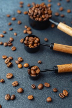 Koyu arkaplanda kaşık ölçmede kahve çekirdekleri
