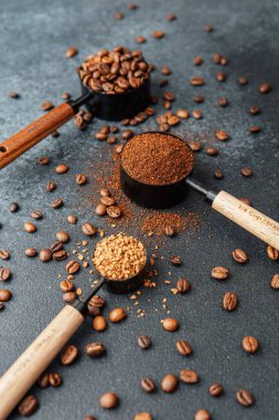 Ground Coffee ve gri arka planda kepçeli fasulyeler.