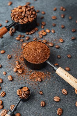 Koyu arka plandaki kepçeleri ölçmek için öğütülmüş kahve ve fasulye.