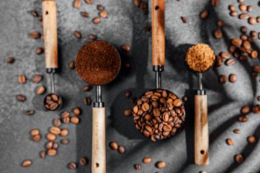 Koyu arkaplan üzerine kepçe ve kase şeklinde çeşitli kahve türleri.