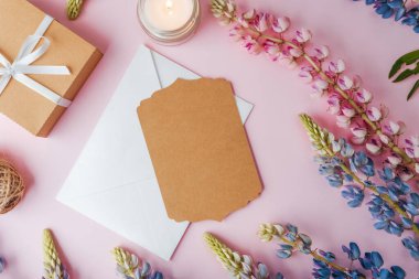 Hediye kutusu, zarf ve pembe arka planda çiçekli mum.