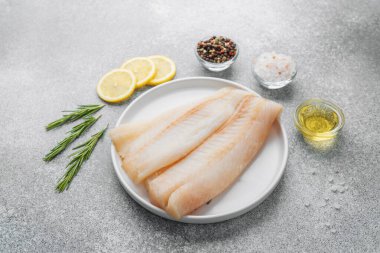 Gri arka planda baharat içeren ham pollock fileto.