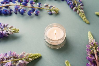 Yeşil arka planda mum ve lupin çiçekleri