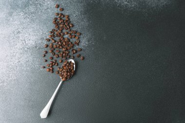 Koyu arkaplanda metal kaşıkta kahve çekirdekleri