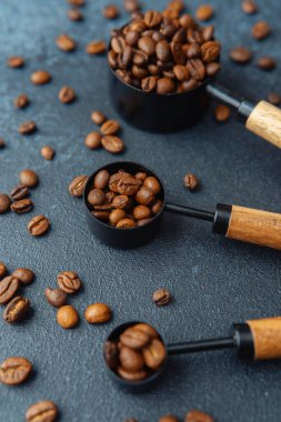 Koyu arkaplanda kaşık ölçmede kahve çekirdekleri