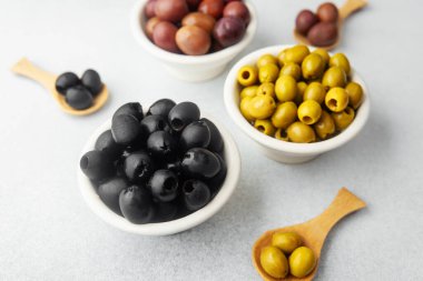 Gri arkaplandaki zeytinler, yeşil zeytinler, siyah ve kalamata zeytinleri.