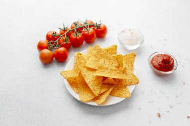 Domatesli nacho cipsi, beyaz arka planda tuz ve sos.