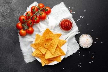 Taze domatesli nacho, beyaz örtülü salsa ve tuz koyu arkaplanda.