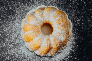 Siyah arkaplanda pudra şekerli kek 