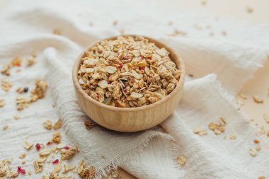 Tahta kasede yumuşak beyaz kumaş arka planda granola.