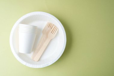 Mavi arkaplanda fincanlar ve çatallarla birlikte tek kullanımlık beyaz sofra takımı