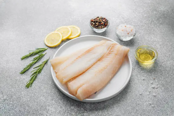 Gri arka planda baharat içeren ham pollock fileto.