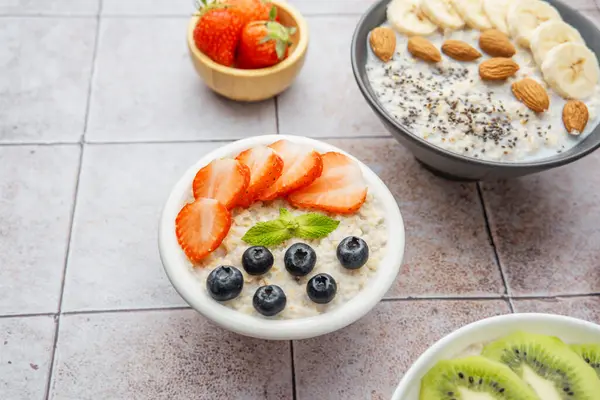 Arka planda muzlu badem kasesi olan çilek ve yulaf ezmesi kasesi.