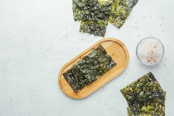 Beyaz arka planda bir kase tuzlu kavrulmuş yosun atıştırmalığı