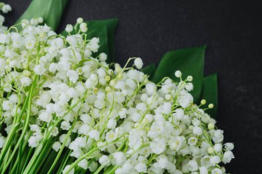 Siyah arka planda yeşil yaprakları olan bir buket nilüfer çiçeği.