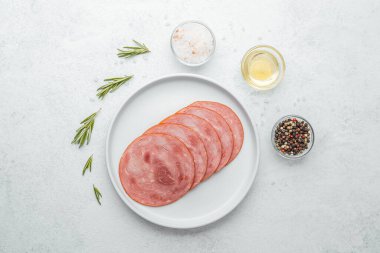 Beyaz tabakta dilimlenmiş sosis ve baharat.