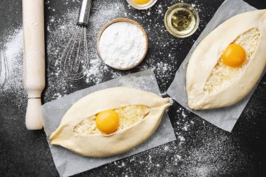 Un kaplı yüzeyinde yumurta sarısı olan iki çiğ khachapuri.