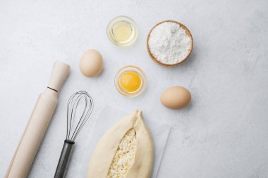 Beyaz zemin üzerinde yumurta sarısı ve peynirli çiğ khachapuri.