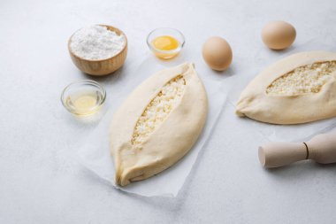 Beyaz mutfak yüzeyinde peynir ve pişirme aletleriyle Khachapuri