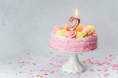 Bir çocuğun ikinci doğum gününü kutlamak için mumla süslenmiş pembe bir pasta..