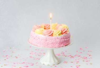 Mum ve konfetiyle pembe ve sarı bir pasta stantta oturur..