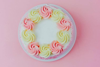 Pastanın üstünde pembe ve beyaz kremalı nefis yuvarlak pasta var..