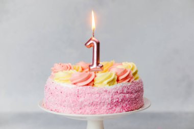 Güzel dekore edilmiş pembe bir pasta bir çocuğun ilk doğum gününü kutlamak için bekliyor..