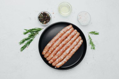 Siyah tabakta taze domuz sosisi, biberiye ve tuz.